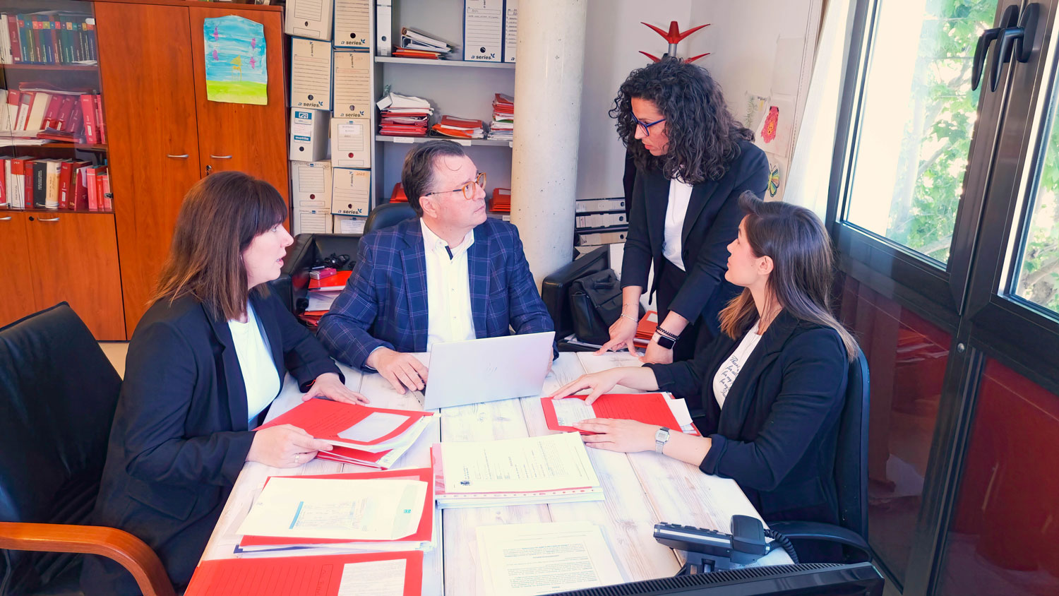 el equipo de Assessoria Florit reunido en una mesa con documentación de los clientes, coordinando el trabajo